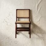 Chandigarh cane dining chair front view against a plaster wall