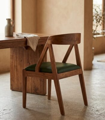 Ela solid wood dining chair at a dining table in a stone-floored room