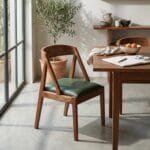 Ela dining chair with green leather seat beside a laid dining table