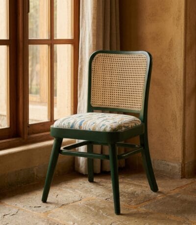 Goa green cane dining chair beside a window in a rustic interior