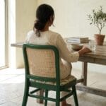 Guest seated on the Goa cane dining chair at a wooden table