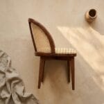 Kaen cane dining chair styled against a draped linen backdrop