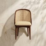 Kaen cane dining chair angled view against a plaster wall