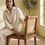 Guest seated on the Moon wooden dining chair in a sunlit interior