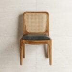 Moon cane dining chair front view against a plaster wall