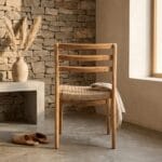 Sara rope-seat dining chair beside a stone wall in a rustic interior