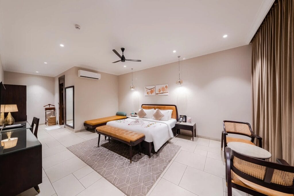 Maira Resort Garden View Suite with solid wood bed, leather headboard, day bed and cane chairs by Samyog Living